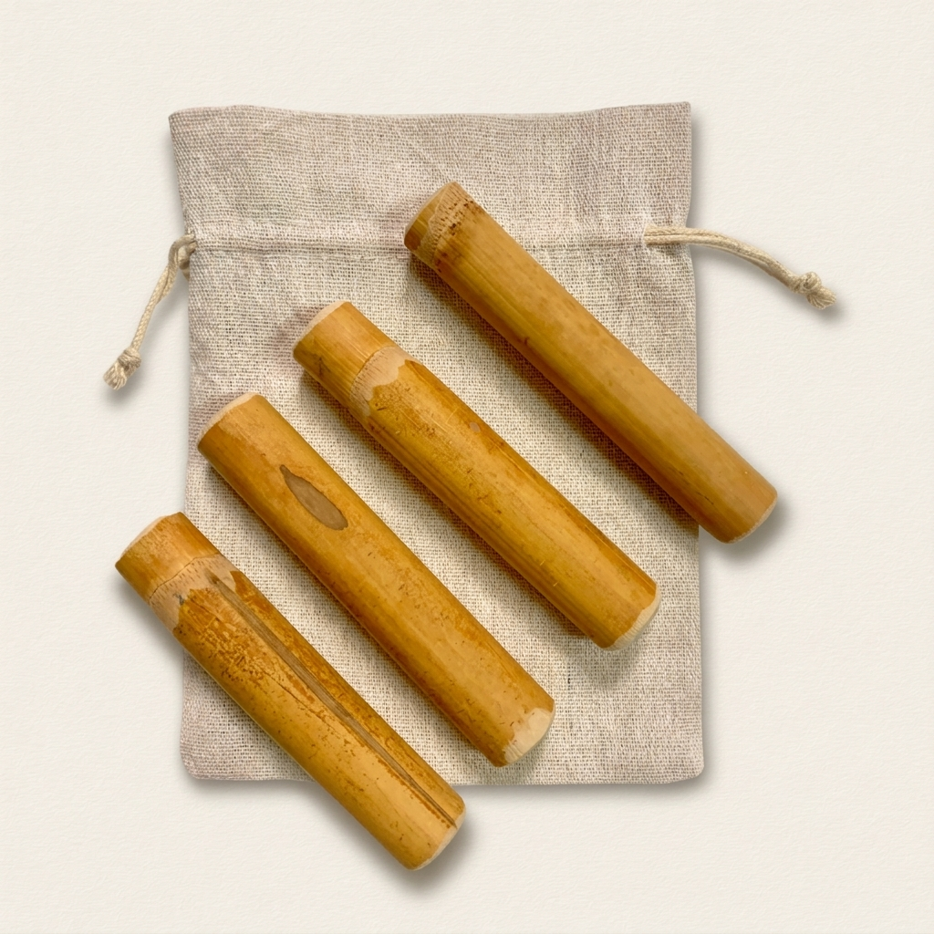 Palos de bambú para bebés: cuatro palos de bambú natural macizo, de tono miel, con nudos y marcas naturales, sobre una bolsita de algodón crudo y fondo claro.